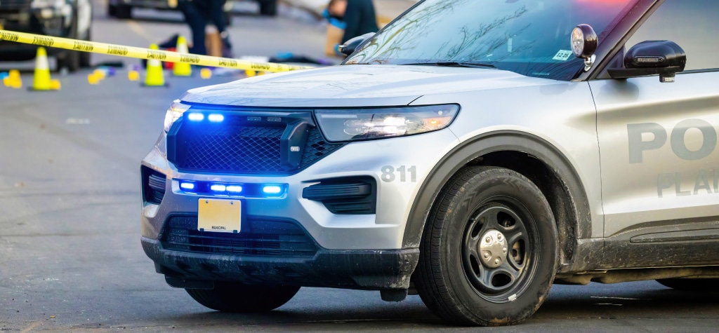 Police vehicle in street in front of crime screen